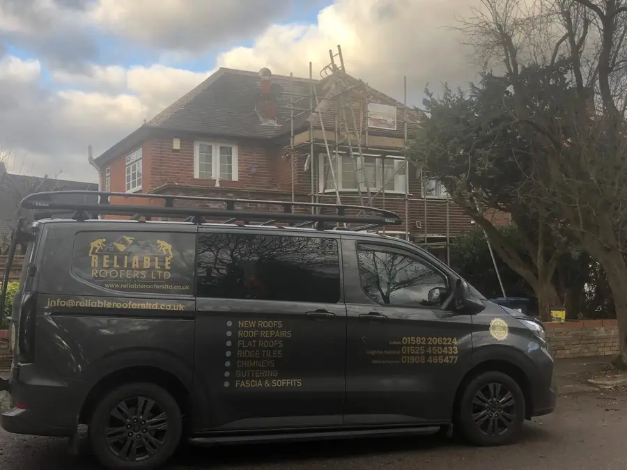Reliable Roofers Ltd sign-written van parked outside a scaffolded house during a re-roof