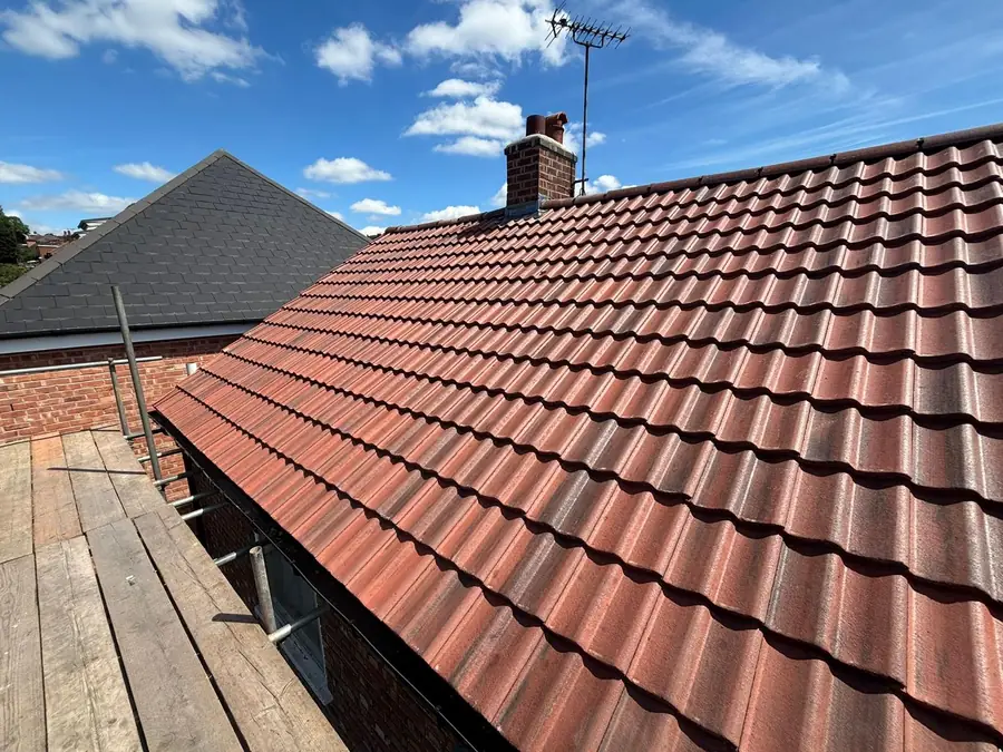 Completed brown interlocking tile roof with scaffold still in place