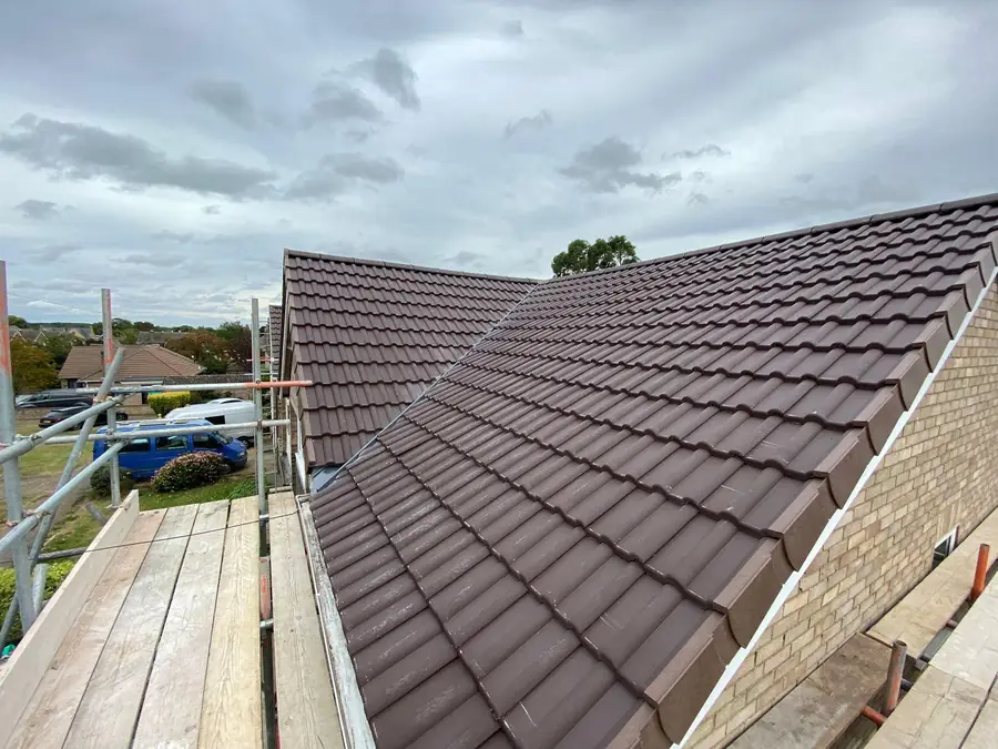 Brown interlocking tiled roof completed, scaffold boards still up