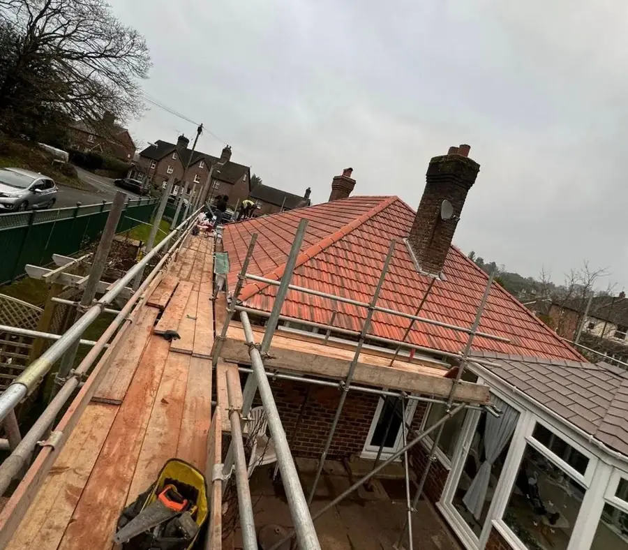 Red tiles going on to a bungalow roof with a chimney, scaffold up