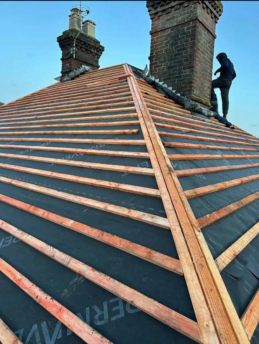 Roofer working at the ridge of a membraned roof beside a chimney