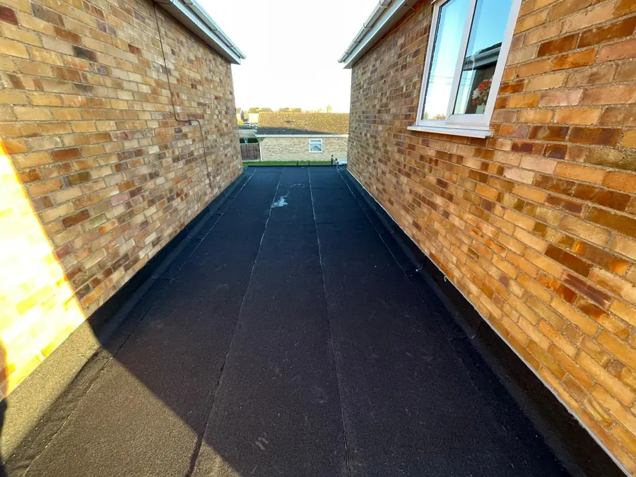 New torch-on felt flat roof between two brick walls
