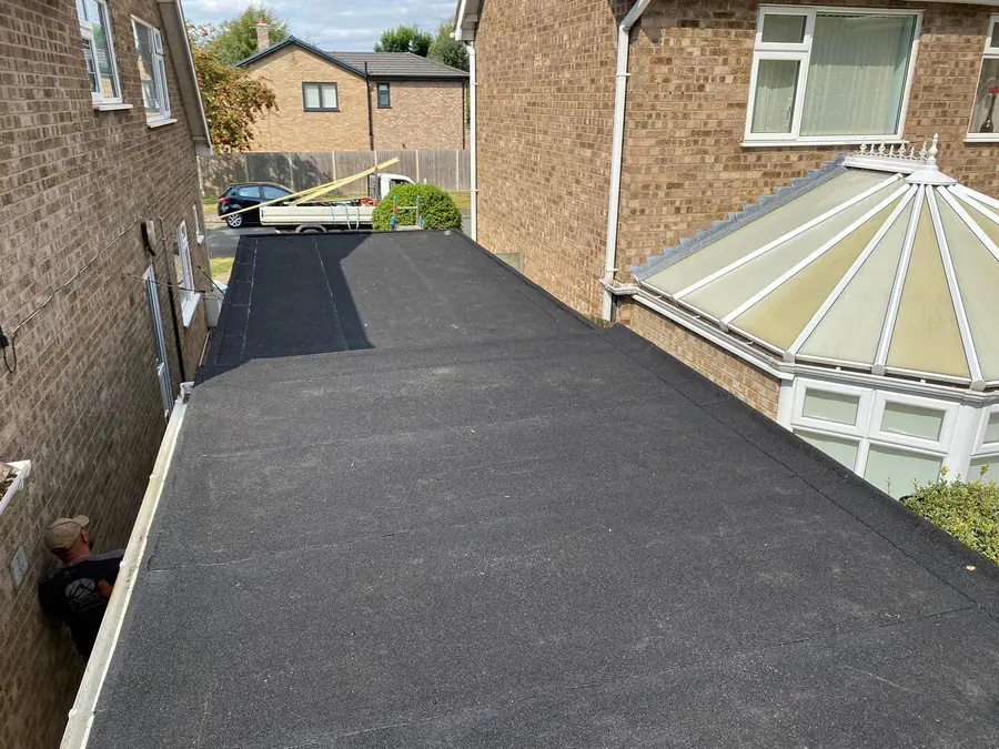 New felt flat roof next to a conservatory