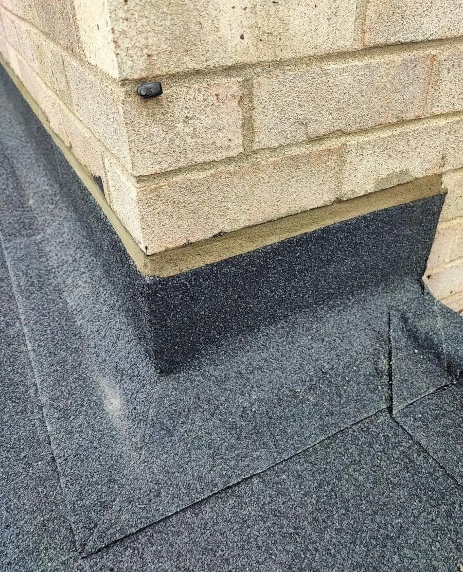 Felt upstand detail against a brick wall on a flat roof
