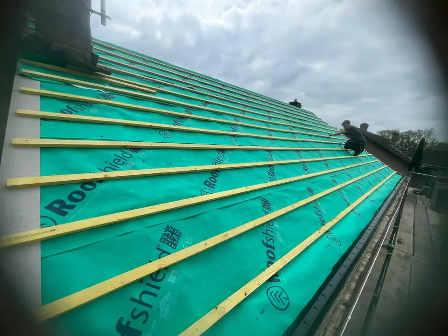 Roofer fixing battens over green membrane