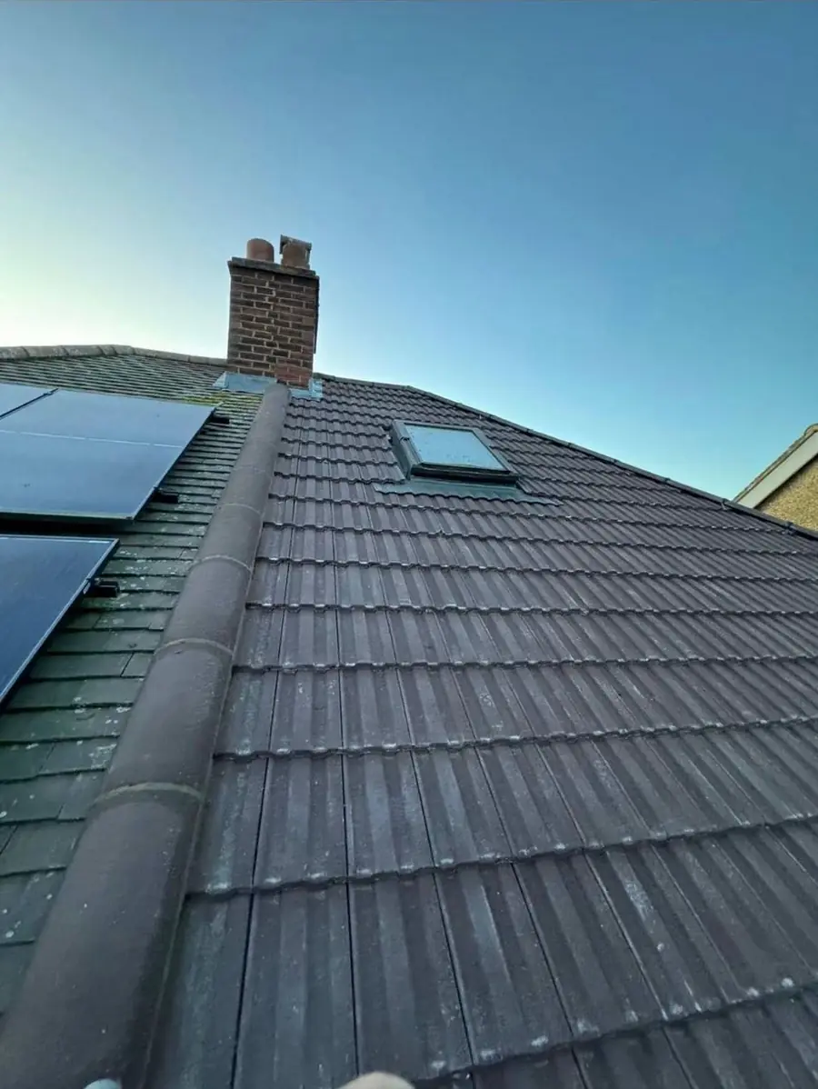 Grey tiled roof with a roof window and solar panels