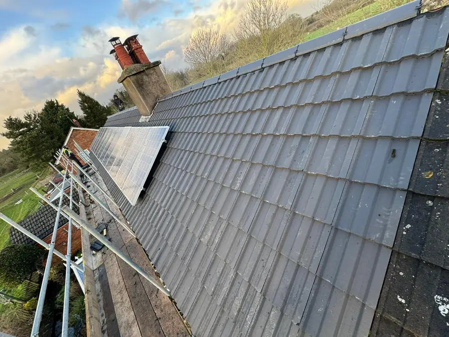 Grey interlocking tiles being laid up to a chimney stack