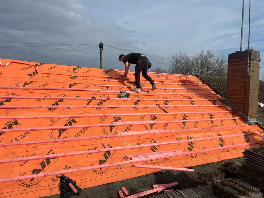 Roofer fixing battens over orange breathable membrane