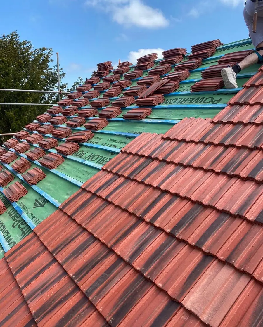 Red interlocking tiles laid over green membrane, close up