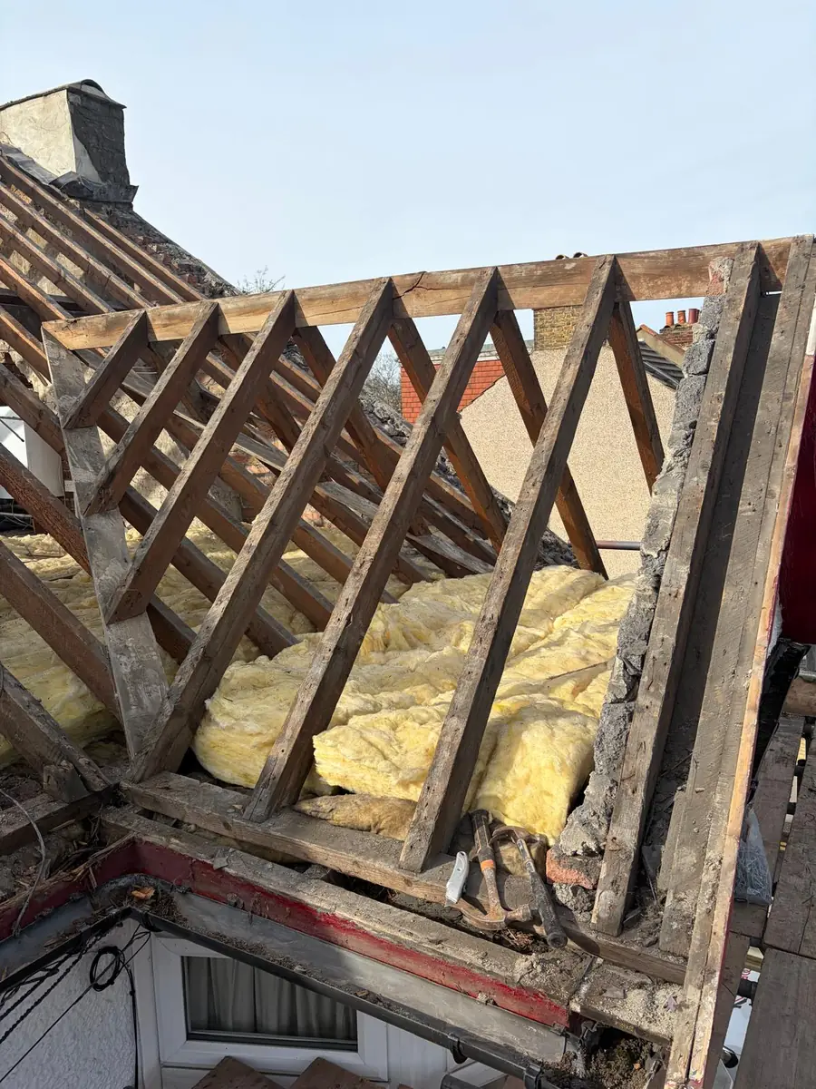 Roof stripped back to the rafters beside a chimney stack before re-roofing